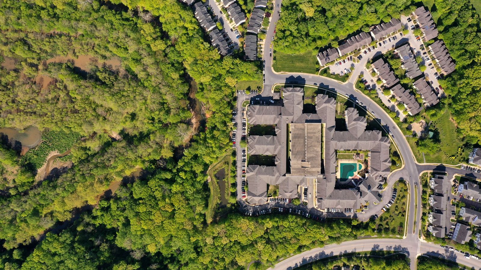 Aerial view of an apartment community bordered by woods