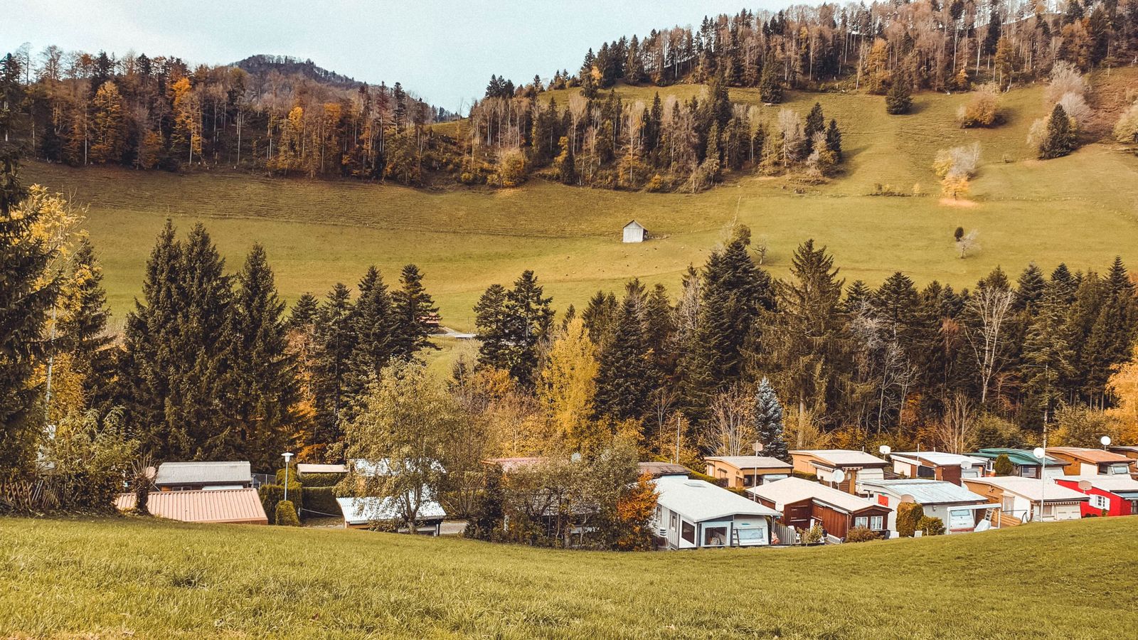 Manufactured home community below wooded hills in fall color